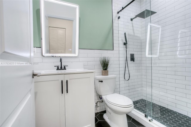 bathroom featuring vanity, a stall shower, tile patterned flooring, tile walls, and toilet