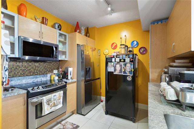 kitchen with decorative backsplash, stainless steel appliances, light countertops, light tile patterned floors, and glass insert cabinets