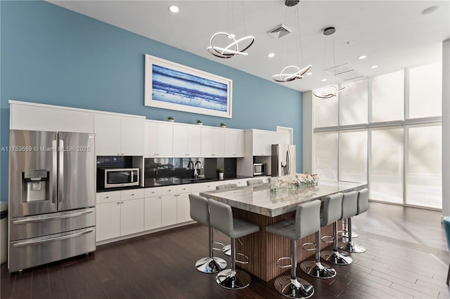 kitchen with a sink, dark wood-type flooring, white cabinets, and stainless steel appliances