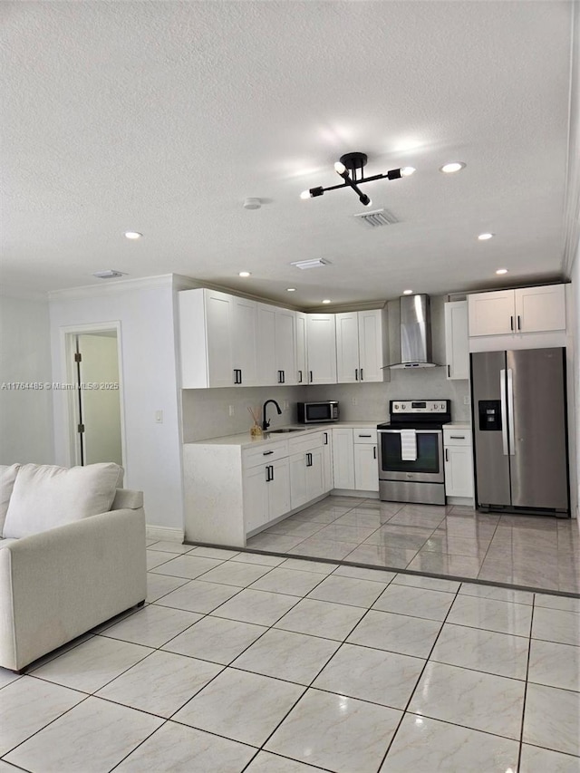 kitchen with visible vents, light countertops, stainless steel appliances, wall chimney exhaust hood, and a sink