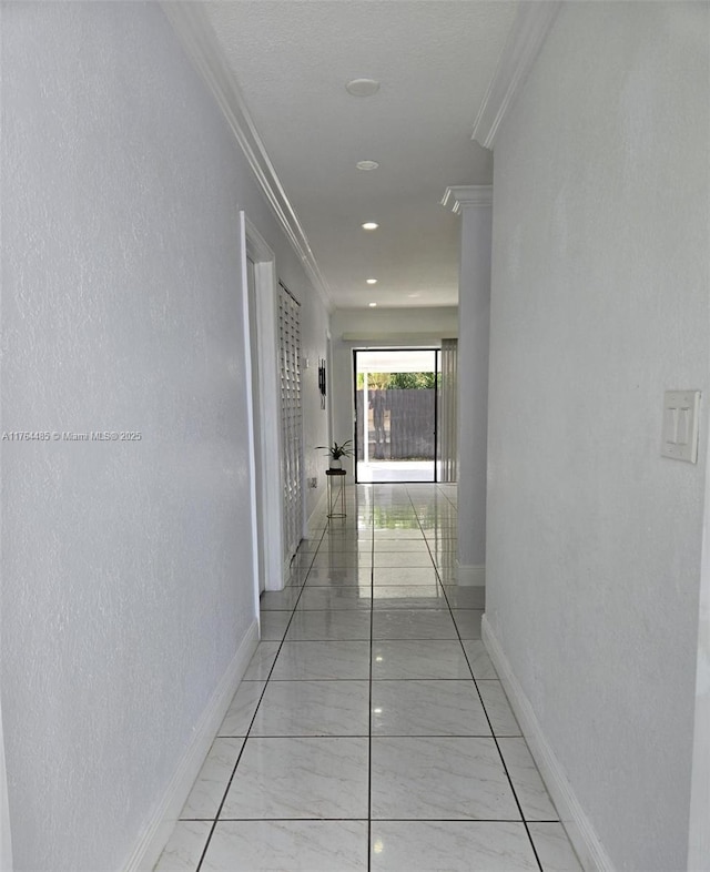 hall featuring marble finish floor, crown molding, baseboards, and a textured wall