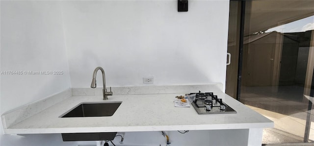 kitchen featuring stainless steel gas cooktop, tile patterned flooring, and a sink