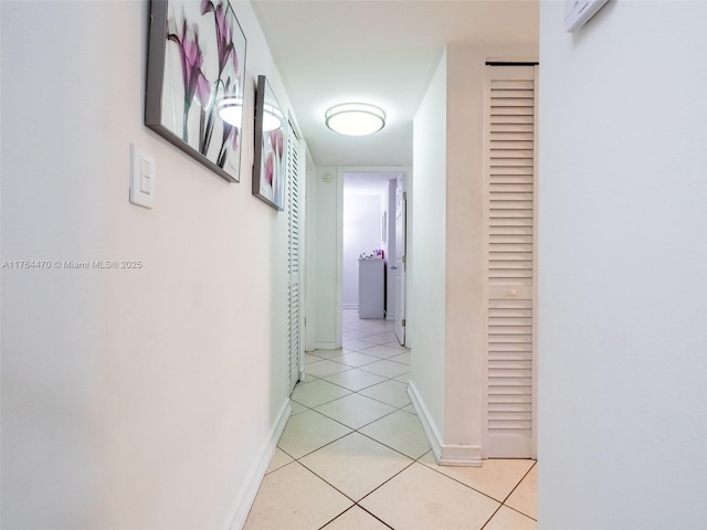 hall featuring light tile patterned floors and baseboards