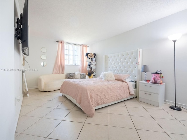 bedroom featuring light tile patterned flooring, baseboards, and a textured ceiling