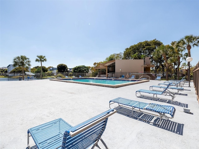 community pool with a patio and fence