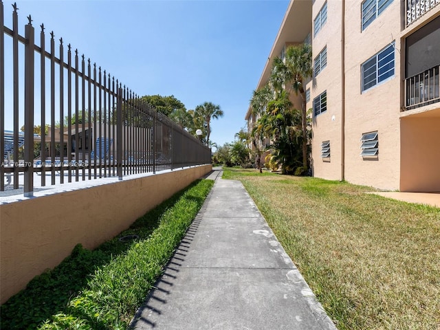 view of property's community featuring a yard and fence