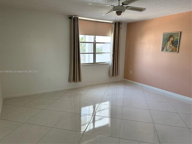 unfurnished room with ceiling fan, light tile patterned floors, baseboards, and a textured ceiling