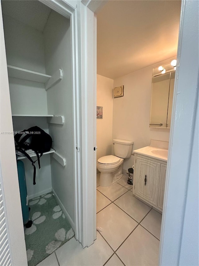 bathroom featuring vanity, tile patterned floors, toilet, and baseboards