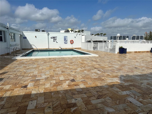 community pool with a patio and fence