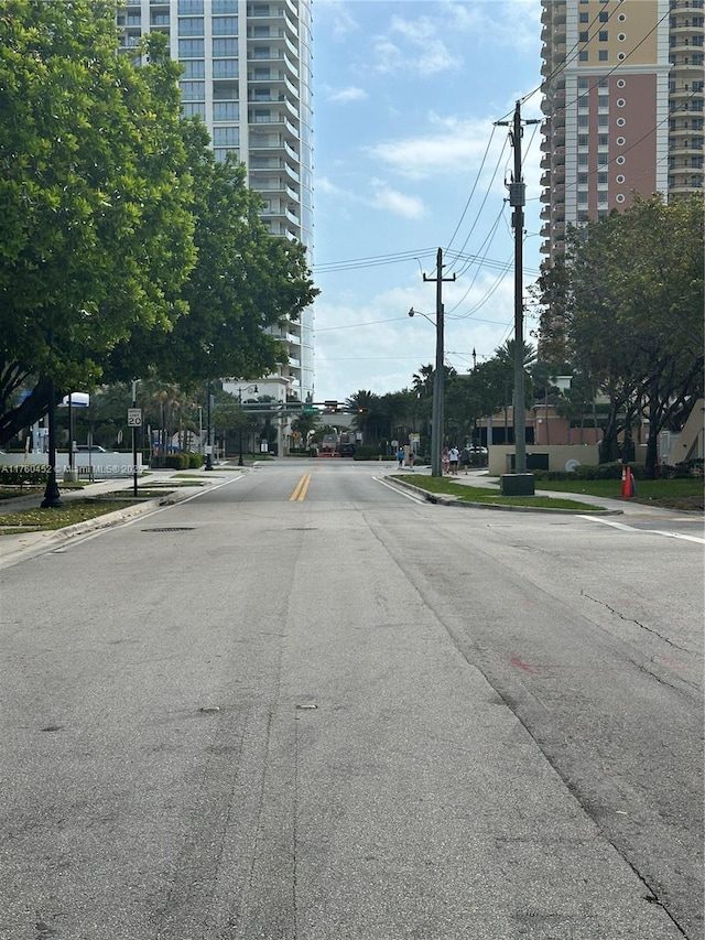 view of road featuring street lights, traffic signs, curbs, and sidewalks