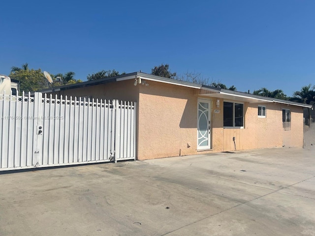 view of home's exterior with stucco siding, fence, and a gate