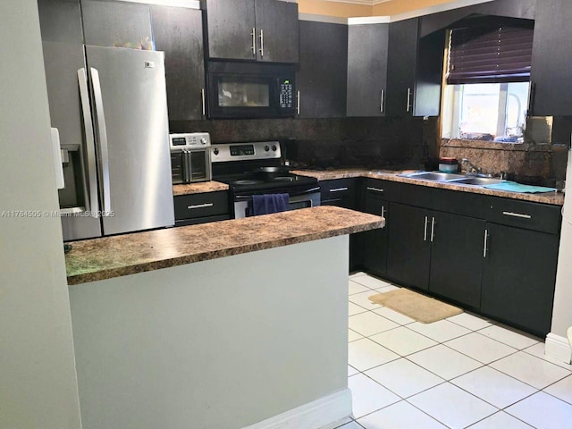 kitchen with a sink, dark cabinetry, stainless steel appliances, a peninsula, and light tile patterned floors