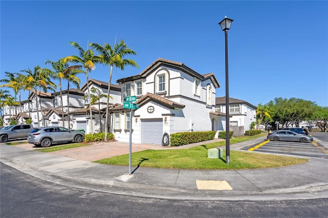 multi unit property with a residential view, a front lawn, an attached garage, and a tiled roof