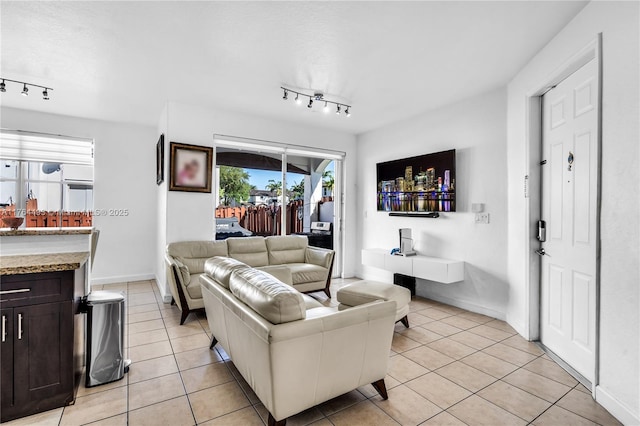 living area featuring track lighting, light tile patterned flooring, and baseboards