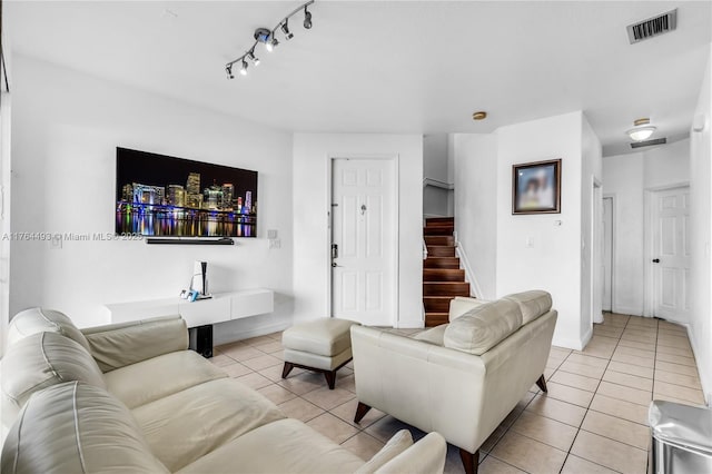 living area featuring stairs, light tile patterned flooring, and visible vents