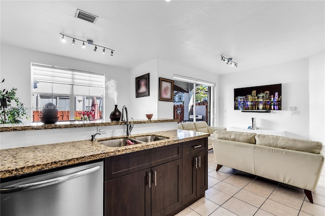 kitchen with light tile patterned floors, a sink, dark brown cabinets, dishwasher, and open floor plan