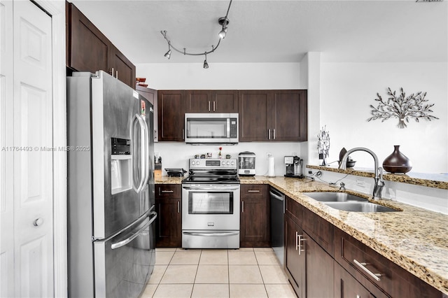 kitchen featuring a sink, light stone countertops, appliances with stainless steel finishes, and light tile patterned floors