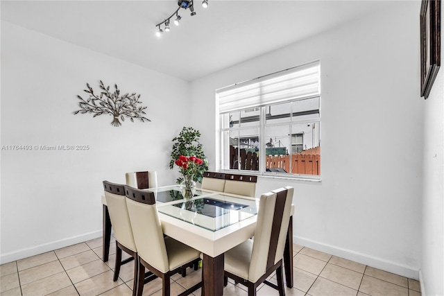 tiled dining room featuring track lighting and baseboards