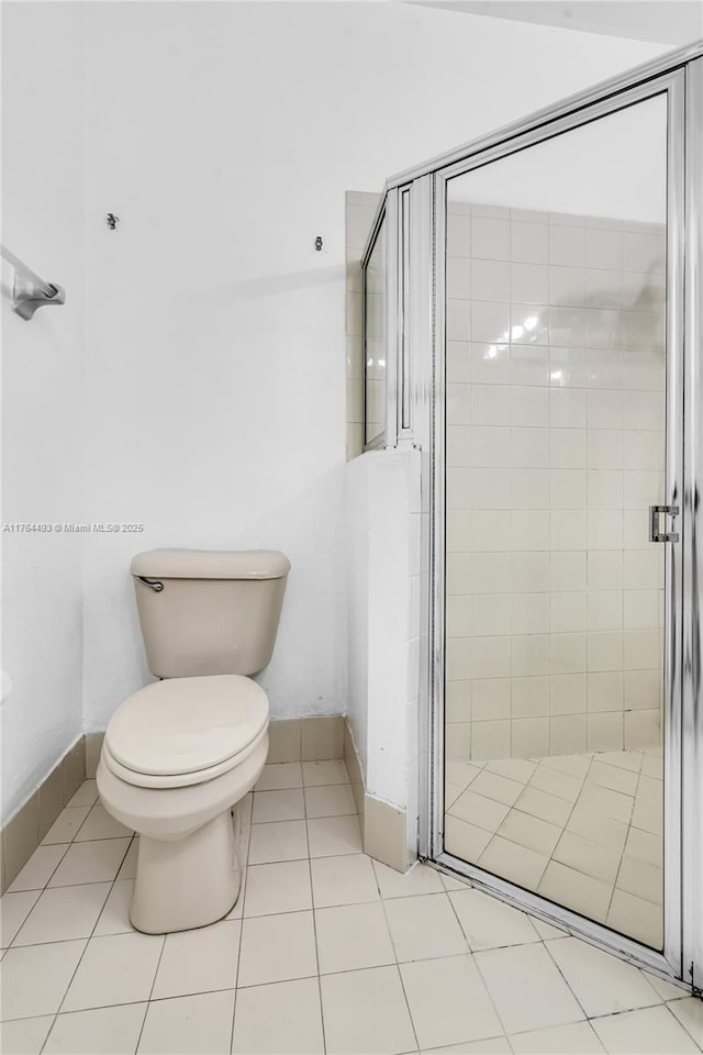 bathroom with tile patterned flooring, a shower stall, and toilet