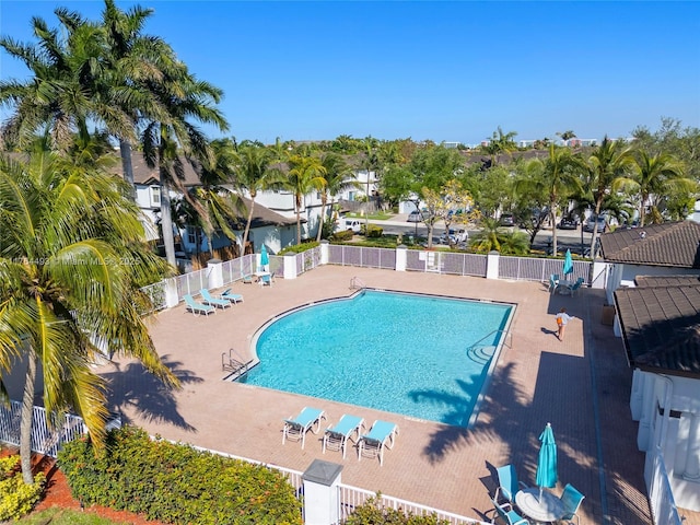 community pool with a patio area and fence