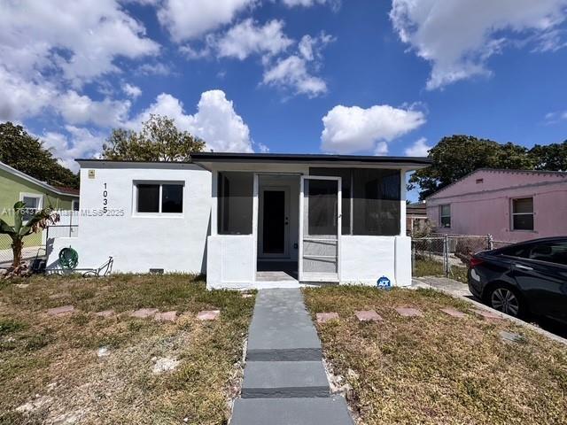 view of front of home with stucco siding, fence, and a sunroom