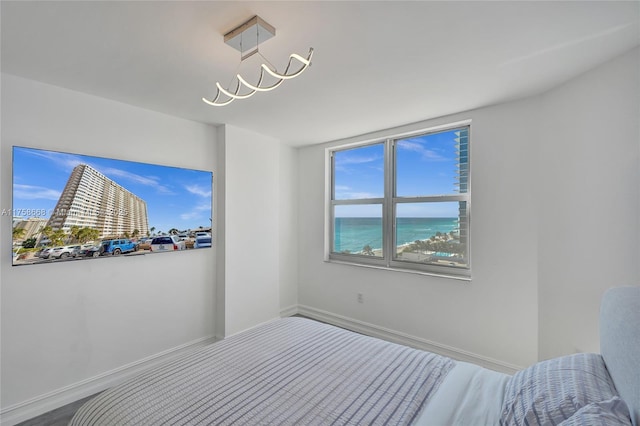 unfurnished bedroom featuring baseboards, an inviting chandelier, and a water view