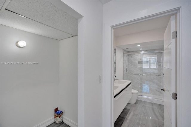 bathroom with vanity, toilet, baseboards, and a stall shower