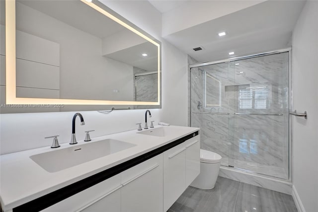 bathroom with a sink, toilet, a stall shower, and double vanity