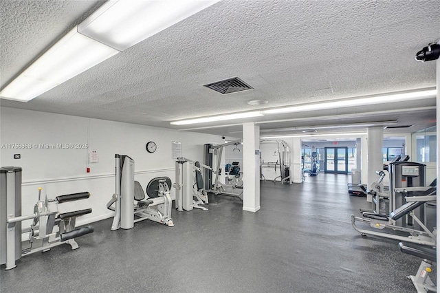 exercise room with baseboards, visible vents, and a textured ceiling