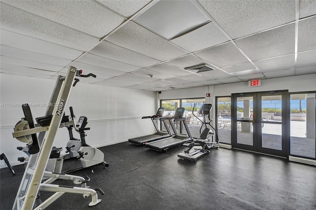 exercise room with a paneled ceiling, visible vents, french doors, and baseboards