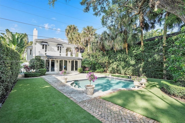 pool with a patio, french doors, and a lawn