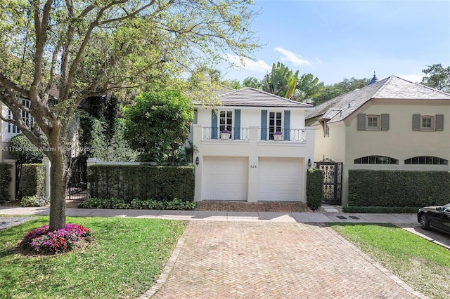 view of front of house featuring stucco siding, decorative driveway, fence, a garage, and a balcony