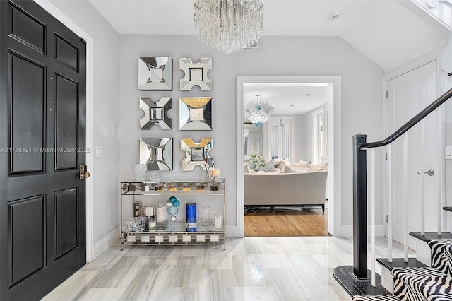 entrance foyer with a chandelier, baseboards, and vaulted ceiling