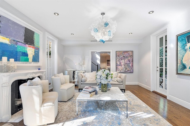 living area featuring wood finished floors, baseboards, a fireplace, recessed lighting, and a chandelier