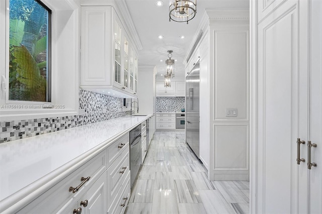 kitchen with a sink, light countertops, appliances with stainless steel finishes, white cabinetry, and tasteful backsplash