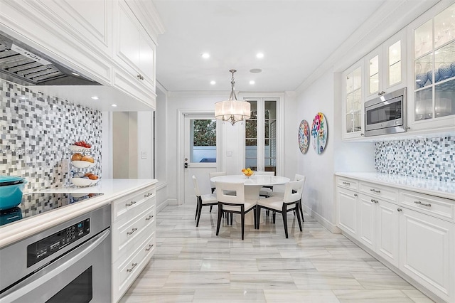 kitchen featuring tasteful backsplash, white cabinetry, stainless steel appliances, and ornamental molding