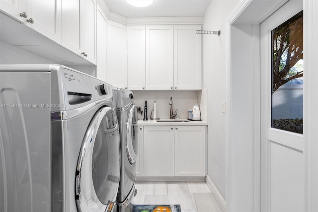 clothes washing area featuring a sink, cabinet space, and separate washer and dryer