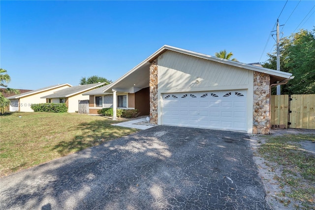 view of front of home featuring a front lawn, fence, a garage, stone siding, and driveway