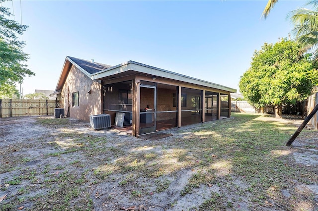 rear view of property featuring stucco siding, central AC, a fenced backyard, and a sunroom