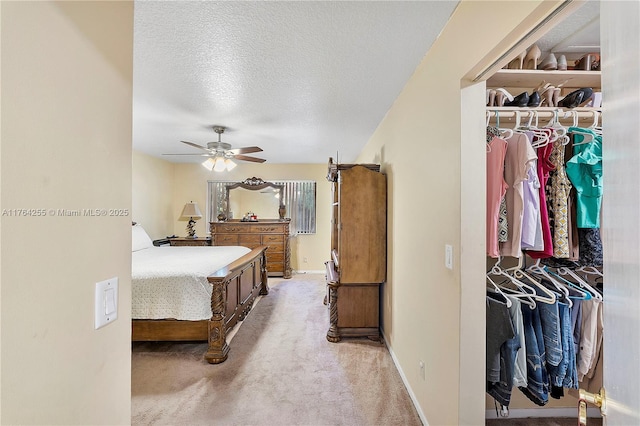 bedroom featuring light colored carpet, a textured ceiling, baseboards, and a ceiling fan