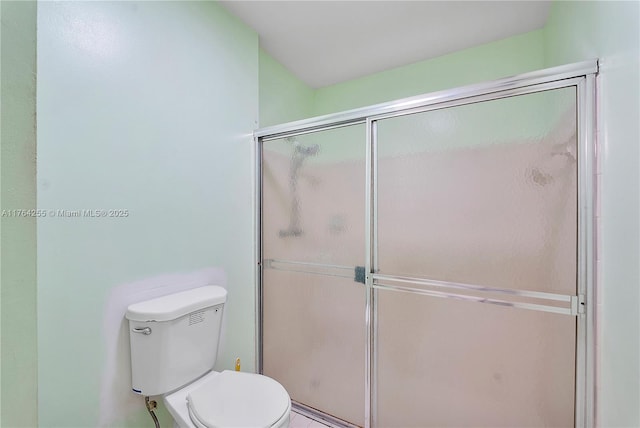 full bathroom featuring a shower with door and toilet