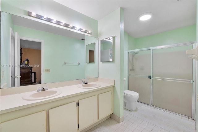 bathroom featuring double vanity, a shower stall, toilet, and a sink