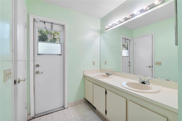 bathroom featuring tile patterned flooring, double vanity, baseboards, and a sink