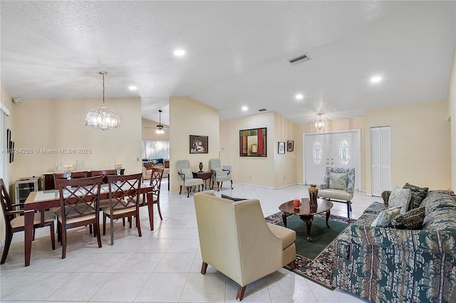 living room featuring visible vents, ceiling fan, lofted ceiling, light tile patterned floors, and a textured ceiling