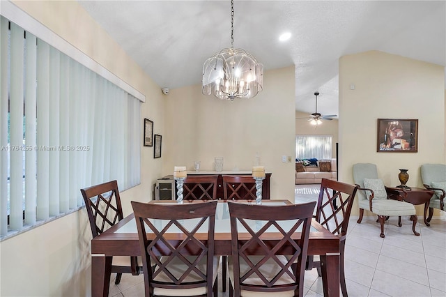 dining space featuring lofted ceiling, light tile patterned floors, ceiling fan with notable chandelier, and baseboards