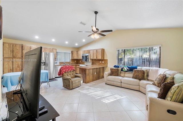 living area with light tile patterned floors, visible vents, lofted ceiling, and ceiling fan