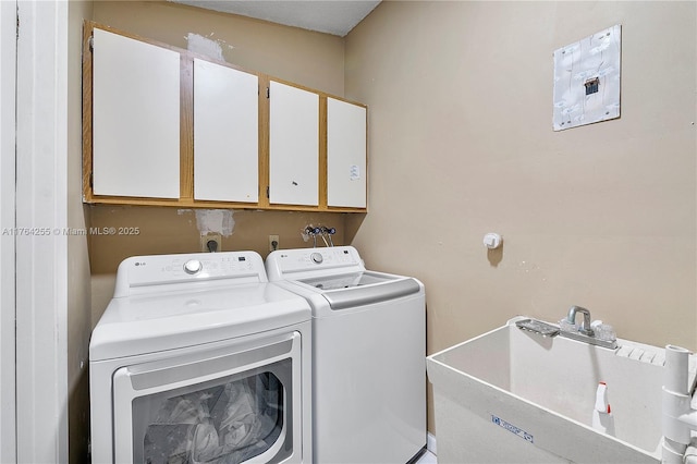 clothes washing area featuring cabinet space, independent washer and dryer, and a sink