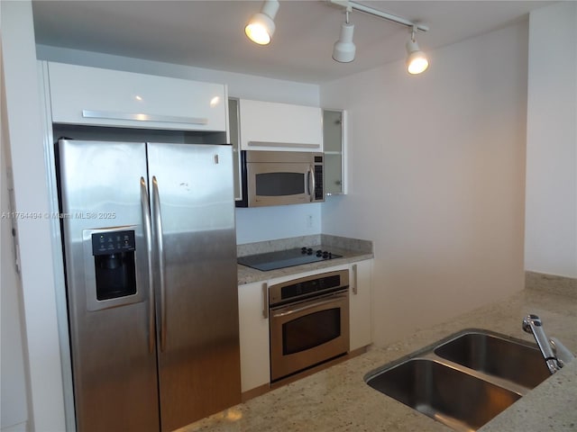 kitchen with light stone counters, white cabinets, appliances with stainless steel finishes, and a sink