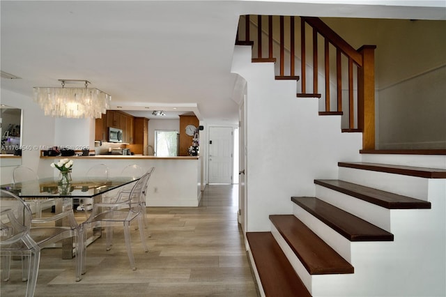 unfurnished dining area featuring baseboards, light wood-style floors, and stairs