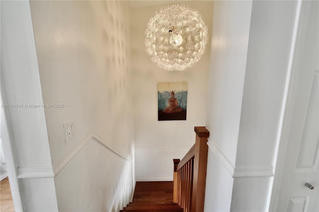 staircase featuring an inviting chandelier and wood finished floors